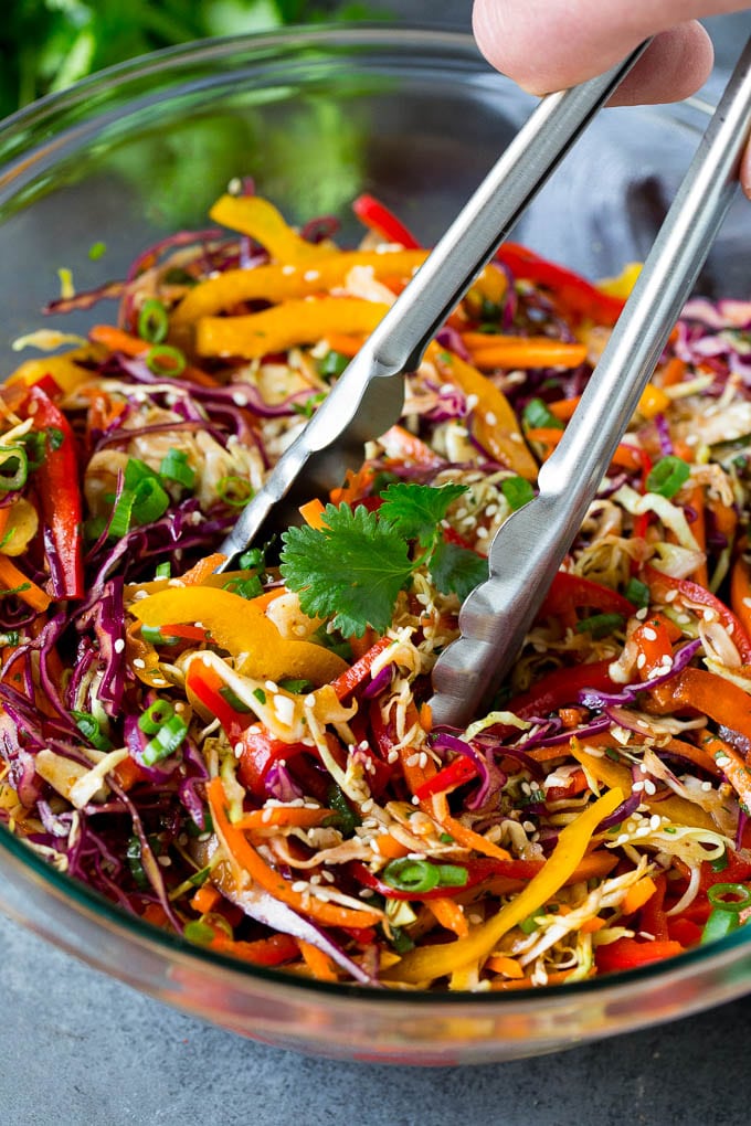 Asian Slaw Recipe #salad #slaw #sidedish #bajap Tongs serving up a portion of Asian slaw.
