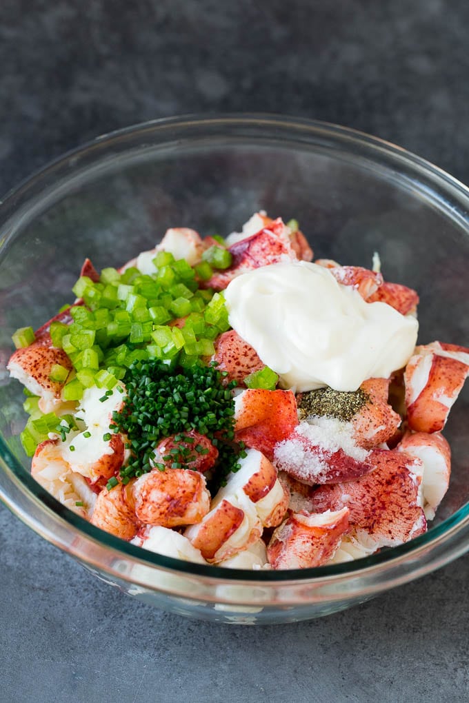 Lobster rolls stuffed with creamy lobster salad in a toasted bun. #lobster #bajap Lobster, chives, celery and mayonnaise in a bowl.