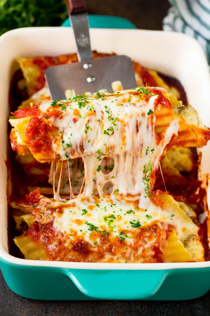 Baked Manicotti Recipe #pasta #cheese #dinner #bajap A spatula serving up a portion of baked manicotti pasta.