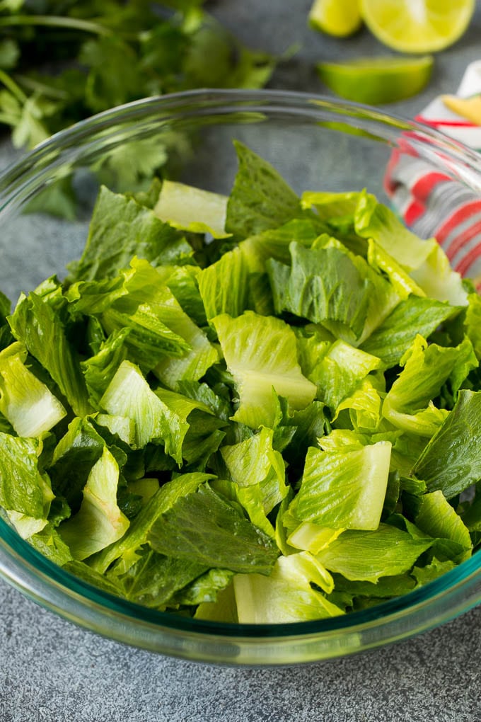 Mexican Salad Recipe #salad #corn #beans #avocado #tomatoes #bajap Chopped romaine lettuce in a bowl.