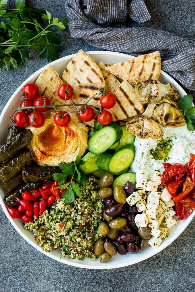 This mezze platter is filled with Mediterranean delicacies including dolmas, hummus, vegetables, pita bread and salads. #appetizer #bajap A mezze platter filled with dips, pita bread, vegetables, olives and cheese.