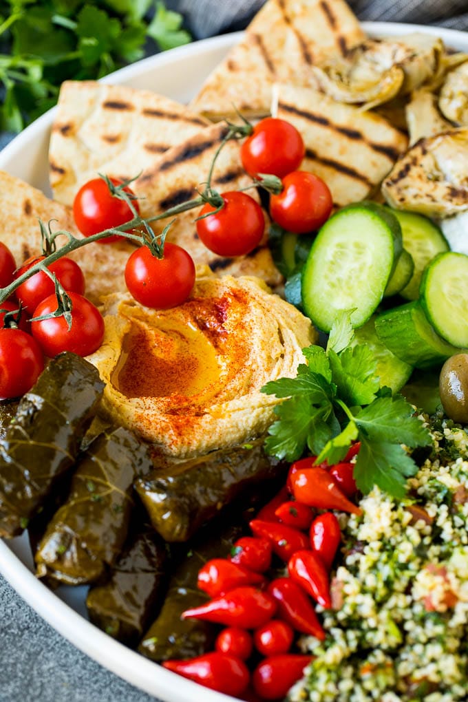 This mezze platter is filled with Mediterranean delicacies including dolmas, hummus, vegetables, pita bread and salads. #appetizer #bajap A Mediterranean mezze platter with hummus, dolmas and vegetables.