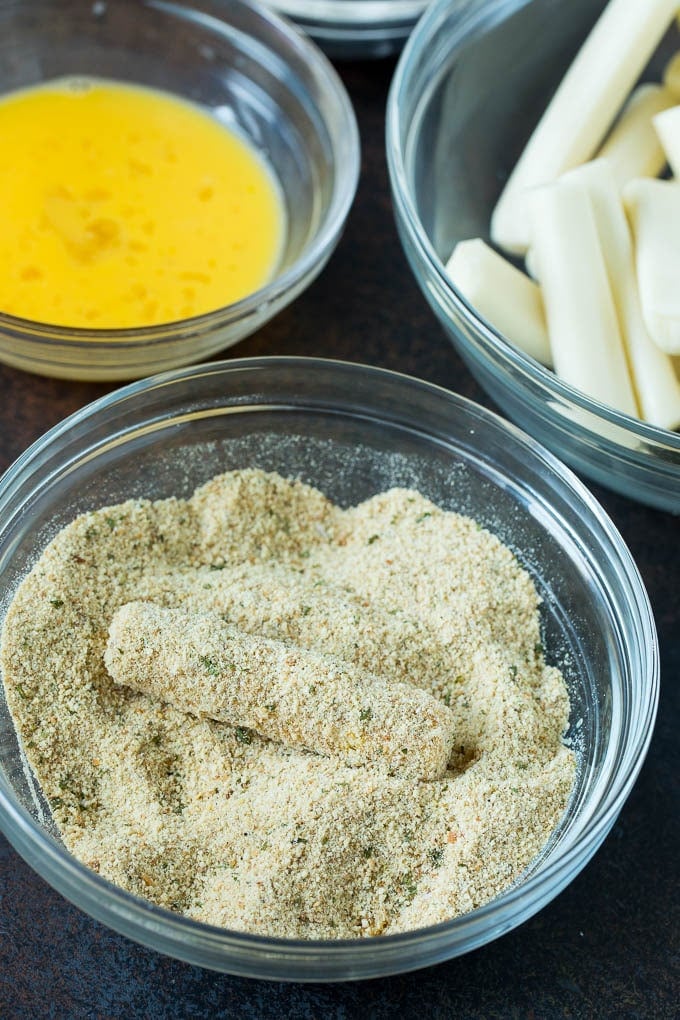 Mozzarella Sticks Recipe #cheese #appetizer #bajap Cheese in a bowl of seasoned breadcrumbs.