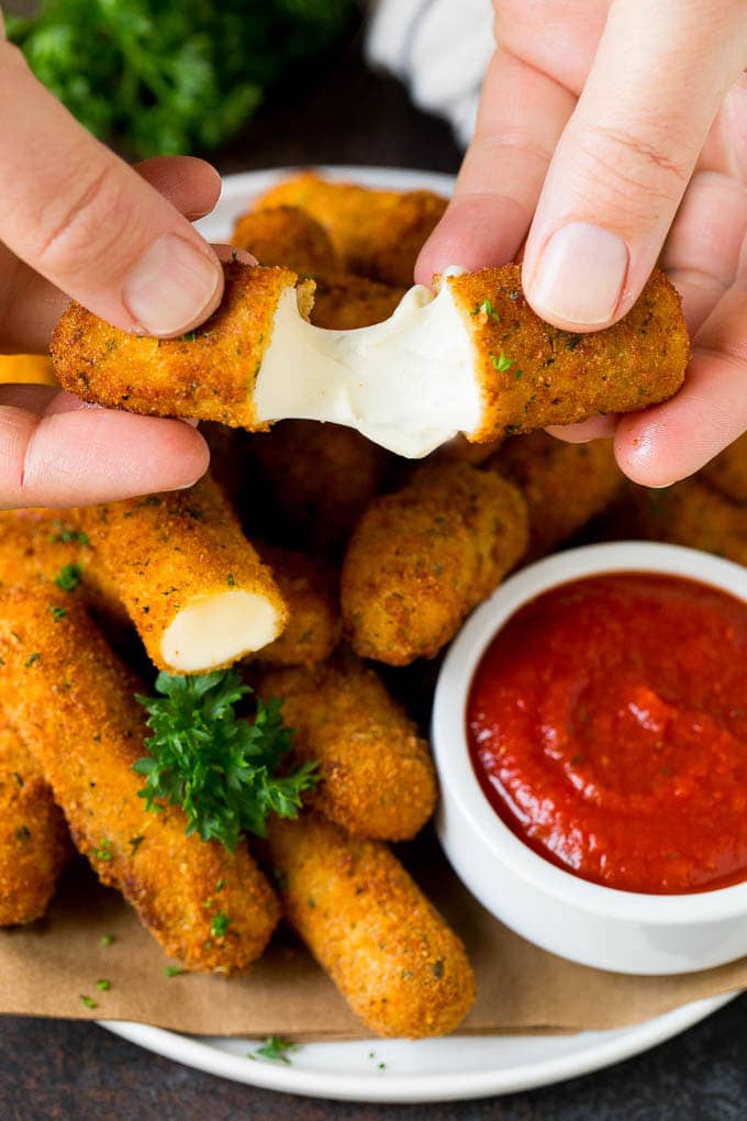 Mozzarella Sticks Recipe #cheese #appetizer #bajap A hand pulling apart mozzarella sticks.