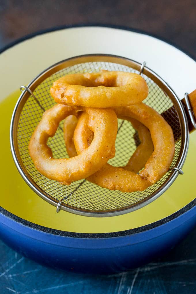 Crispy homemade onion rings that are fried in a flavorful beer batter. #onions #bajap #appetizer Fried onions coming out of a pot of oil.