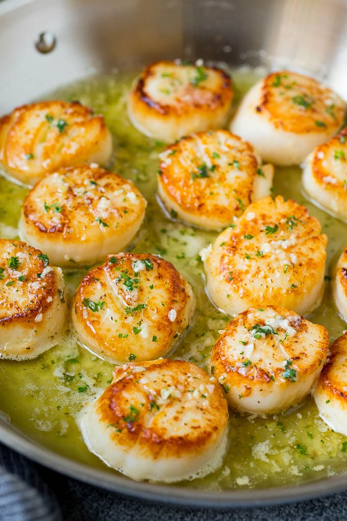 Seared scallops with a garlic and herb butter sauce. An easy and elegant dinner! #seafood #dinner #bajap A pan of scallops in garlic butter.