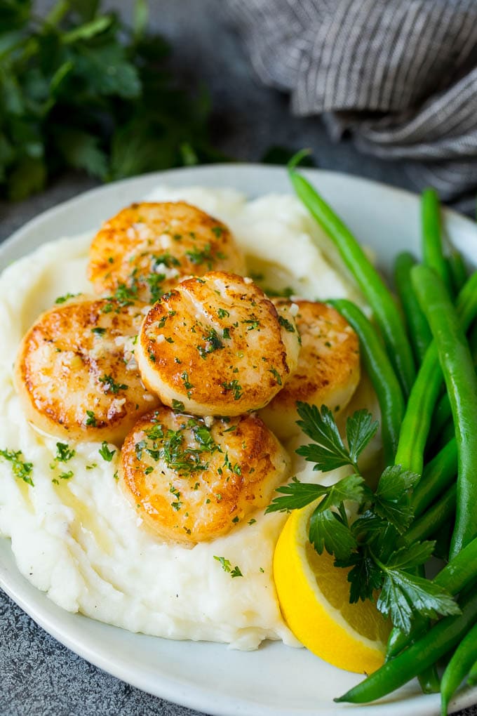Seared scallops with a garlic and herb butter sauce. An easy and elegant dinner! #seafood #dinner #bajap Seared scallops served with mashed potatoes and green beans.