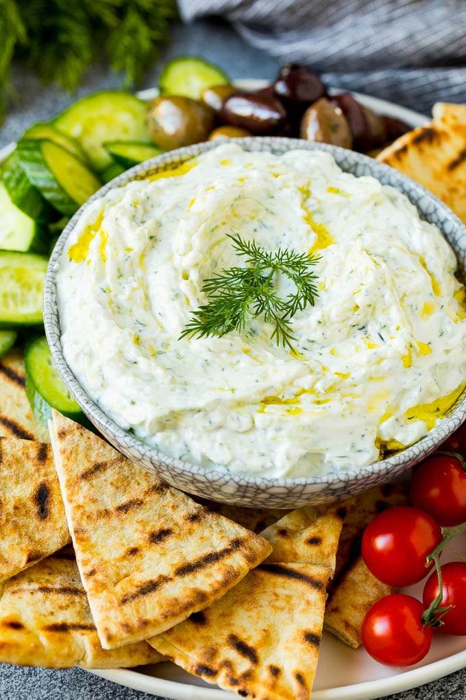The best homemade tzatziki sauce with cucumber and herbs mixed into Greek yogurt. #appetizer #bajap A bowl of tzatziki served with pita bread and vegetables.