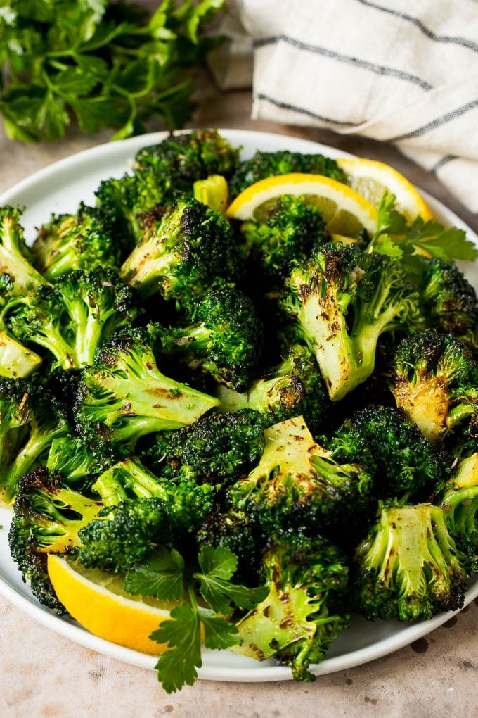 Grilled broccoli is packed with flavor and is a colorful and healthy side dish! #broccoli #bajap Grilled broccoli topped with parsley and garnished with lemon wedges.