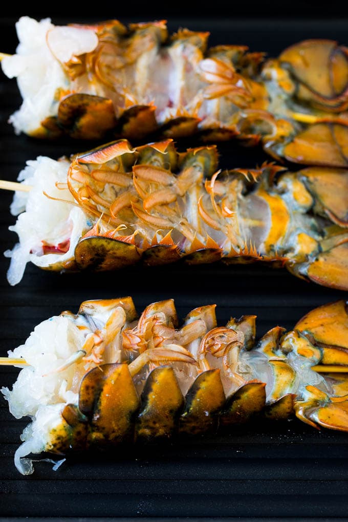 Grilled lobster tail drizzled with garlic butter is an easy and elegant dinner option. #lobster #bajap Lobster tails upside down on a grill pan.