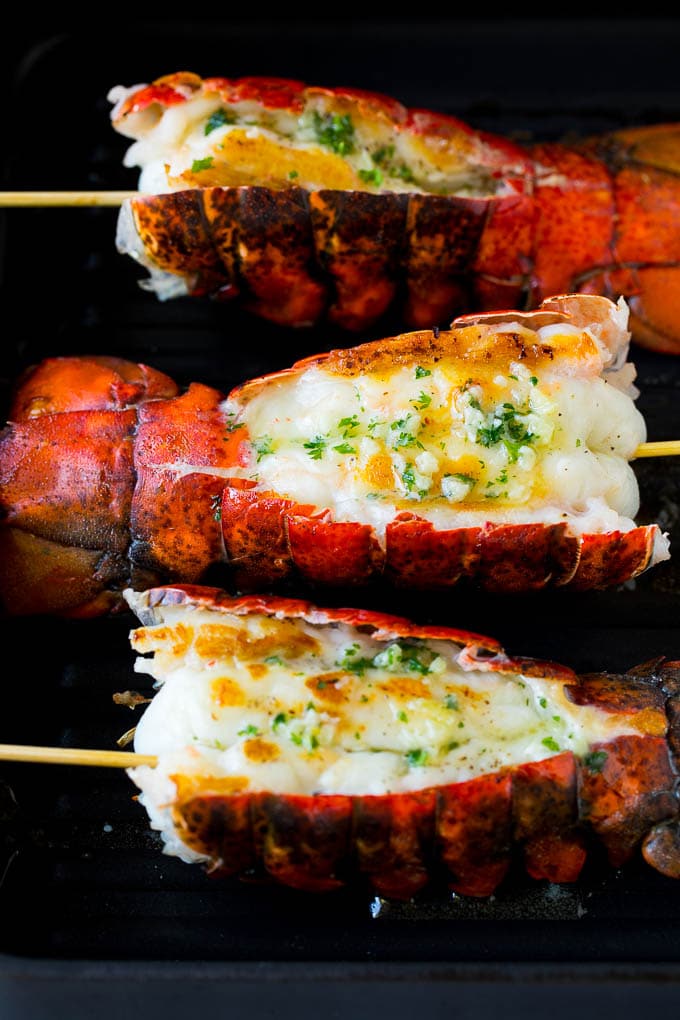 Grilled lobster tail drizzled with garlic butter is an easy and elegant dinner option. #lobster #bajap Cooked lobster tails on a grill pan, brushed with butter.