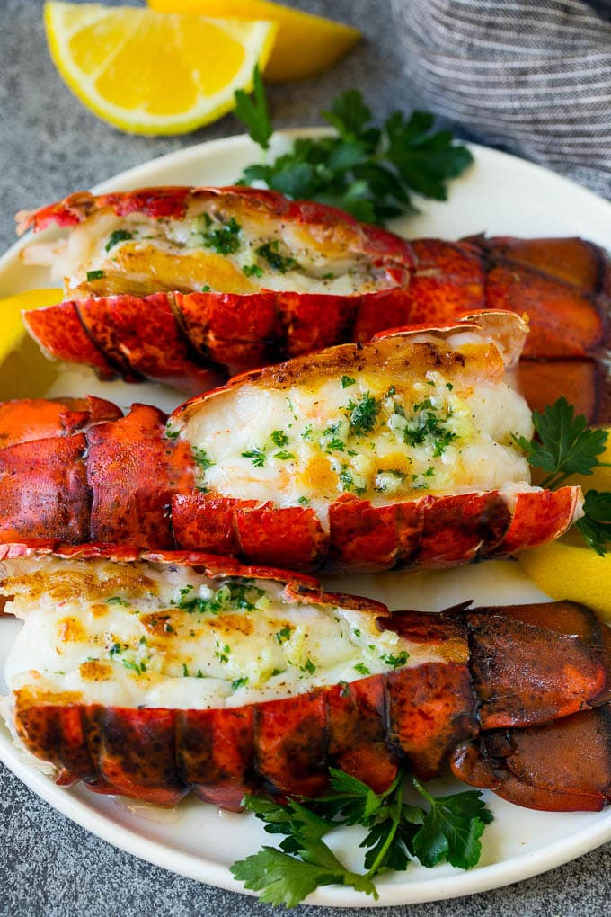 Grilled lobster tail drizzled with garlic butter is an easy and elegant dinner option. #lobster #bajap Grilled lobster tail topped with garlic butter and garnished with lemon and parsley.