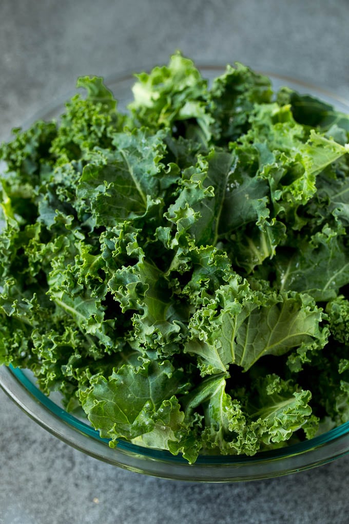 Sauteed kale flavored with olive oil and garlic, a quick and easy side dish! #kale #bajap Chopped kale in a mixing bowl.