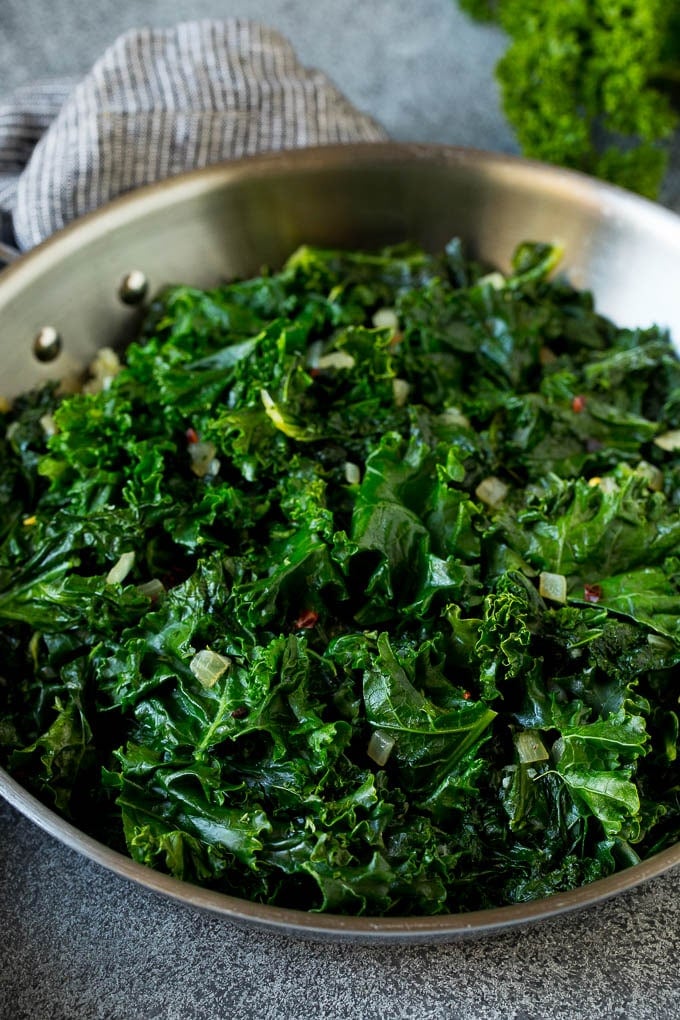 Sauteed kale flavored with olive oil and garlic, a quick and easy side dish! #kale #bajap Cooked kale with olive oil, onions and garlic.