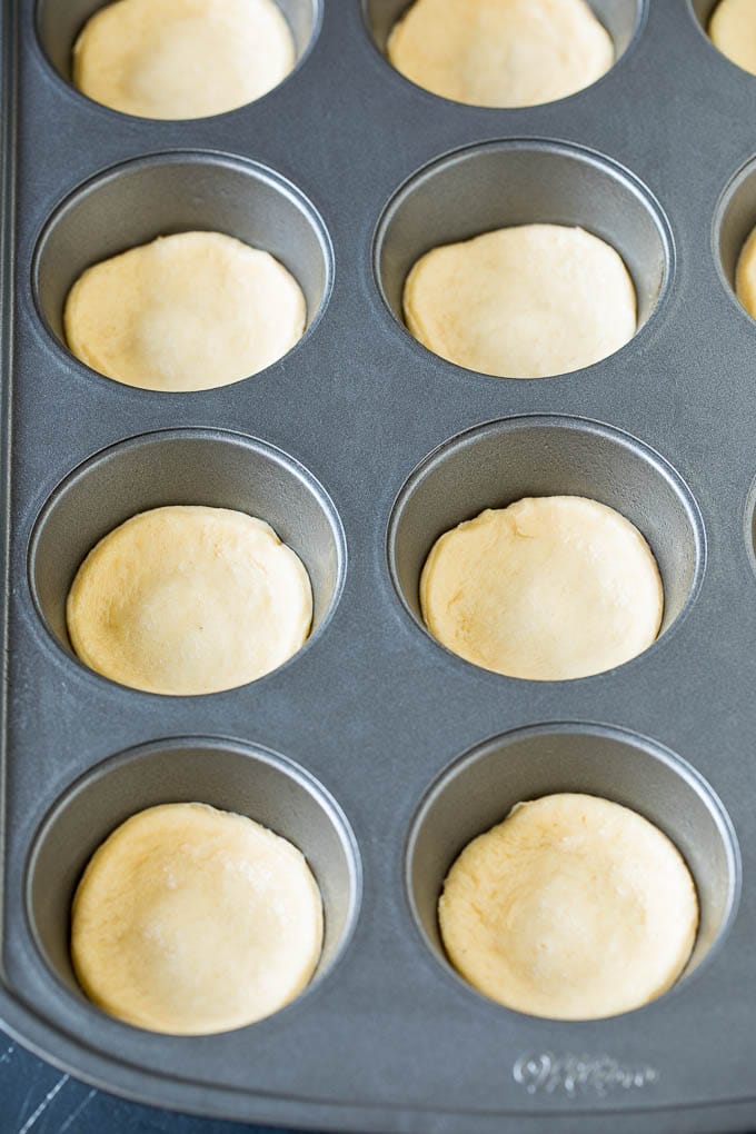 Mini pizzas topped with pepperoni are a fun and easy appetizer option. #pizza #bajap #appetizer Dough circles pressed into muffin cups.