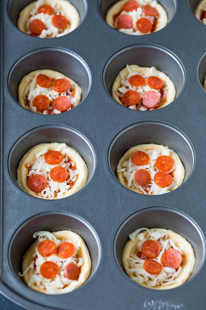 Mini pizzas topped with pepperoni are a fun and easy appetizer option. #pizza #bajap #appetizer Dough topped with sauce, cheese and mini pepperoni.