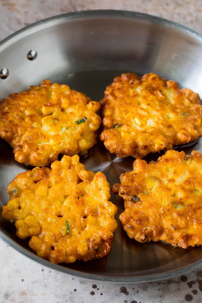 These crispy corn fritters are easy to make and are the perfect appetizer or lighter main course. #corn #bajap Corn cakes in a pan of oil.