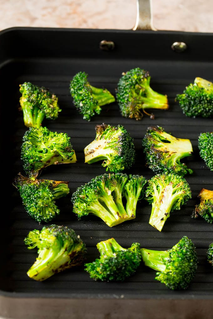 Grilled broccoli is packed with flavor and is a colorful and healthy side dish! #broccoli #bajap Broccoli florets on a grill pan.