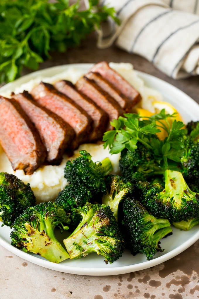 Grilled broccoli is packed with flavor and is a colorful and healthy side dish! #broccoli #bajap Grilled broccoli on a plate with steak and mashed potatoes.