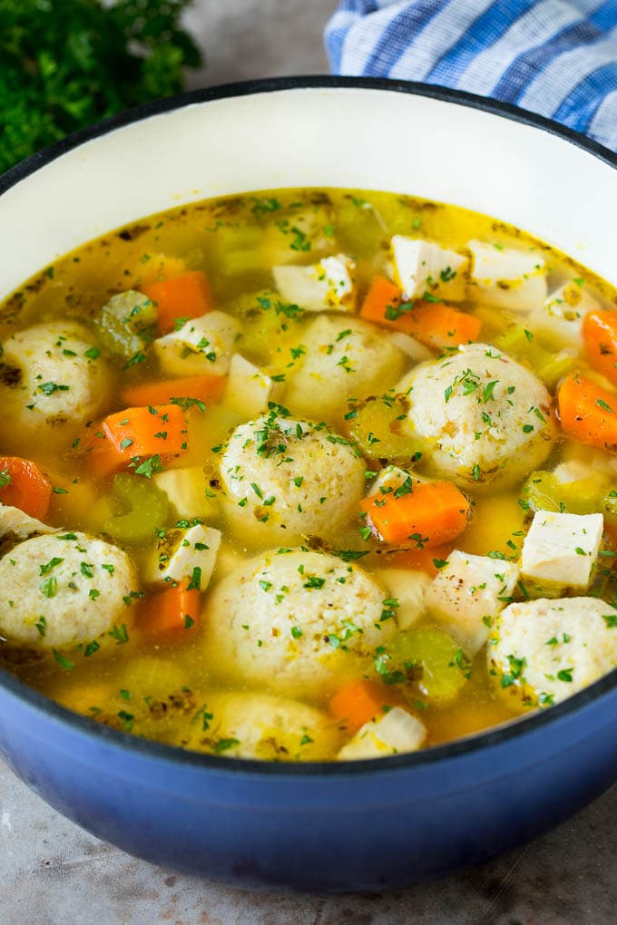 A pot of matzo ball soup with chicken and vegetables.