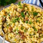 A bowl of dirty rice with a serving spoon in it.