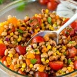 A spoon in a bowl serving up black eyed pea salad.