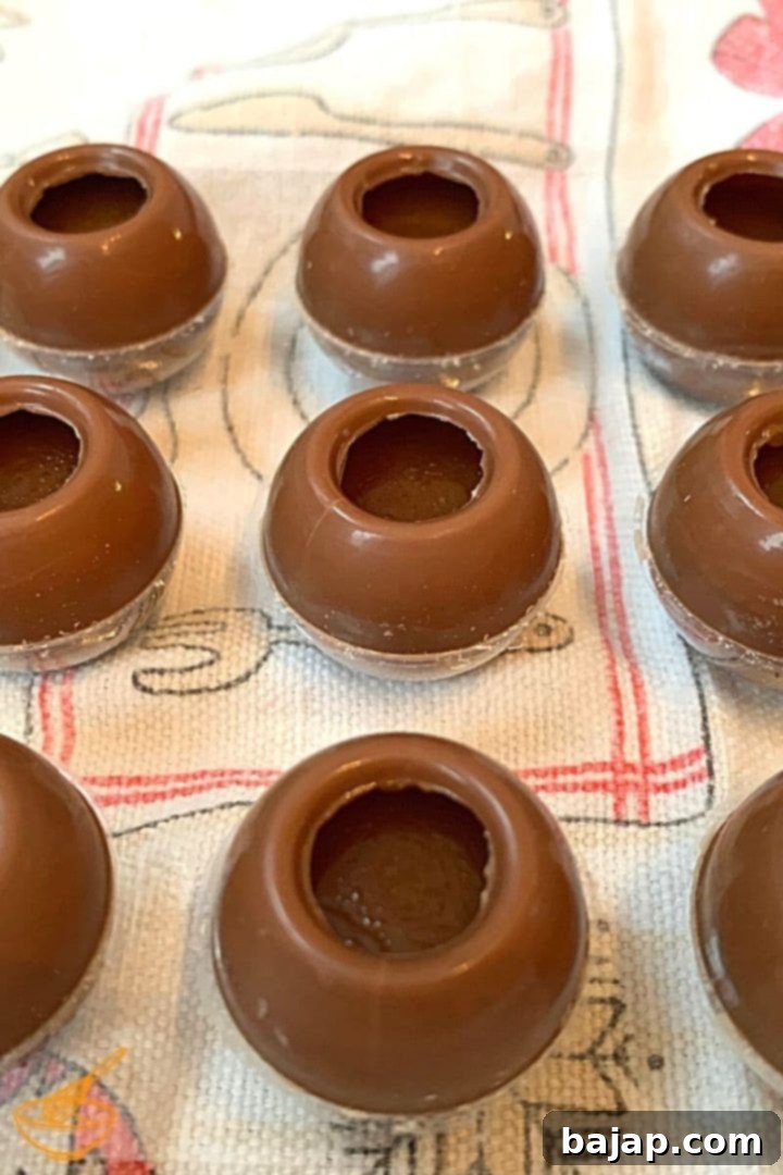 Carefully filling milk chocolate hollow spheres with luscious salted caramel cream, leaving space for sealing.