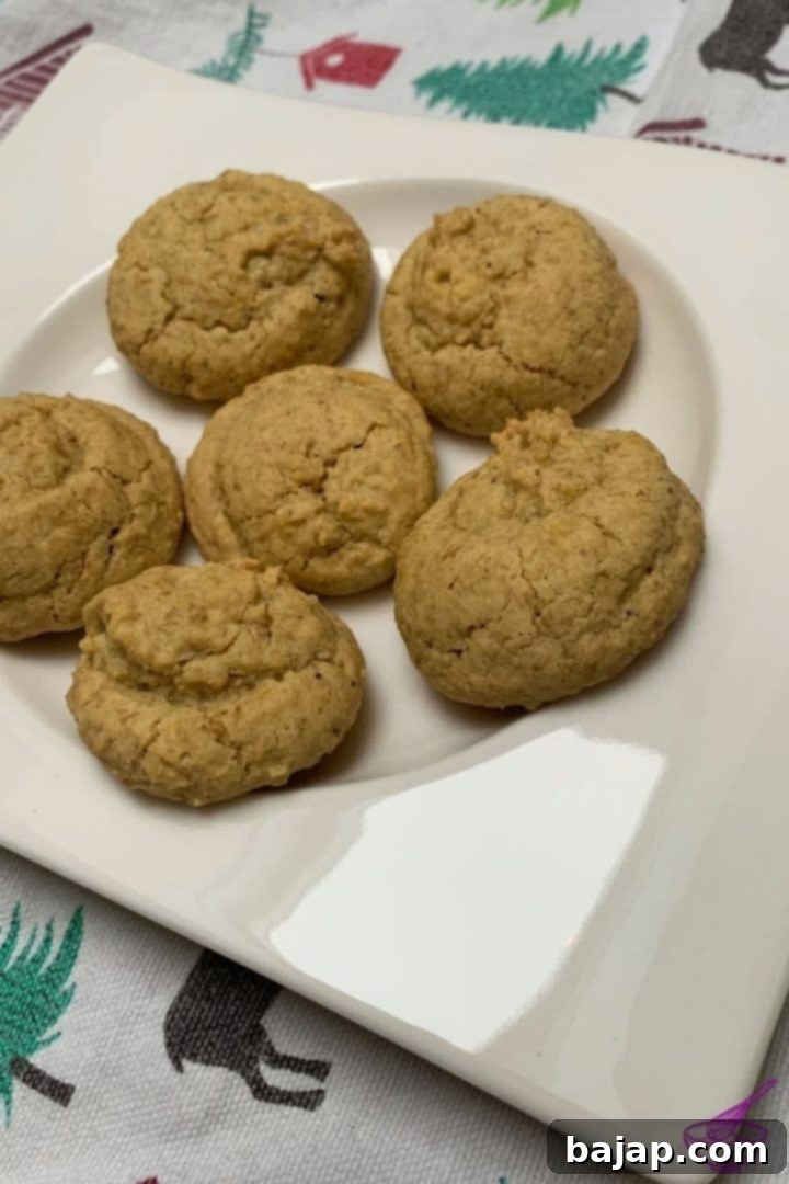Close-up of freshly baked walnut cookies made from leftover egg yolks, garnished with a whole walnut on top, on a cooling rack.
