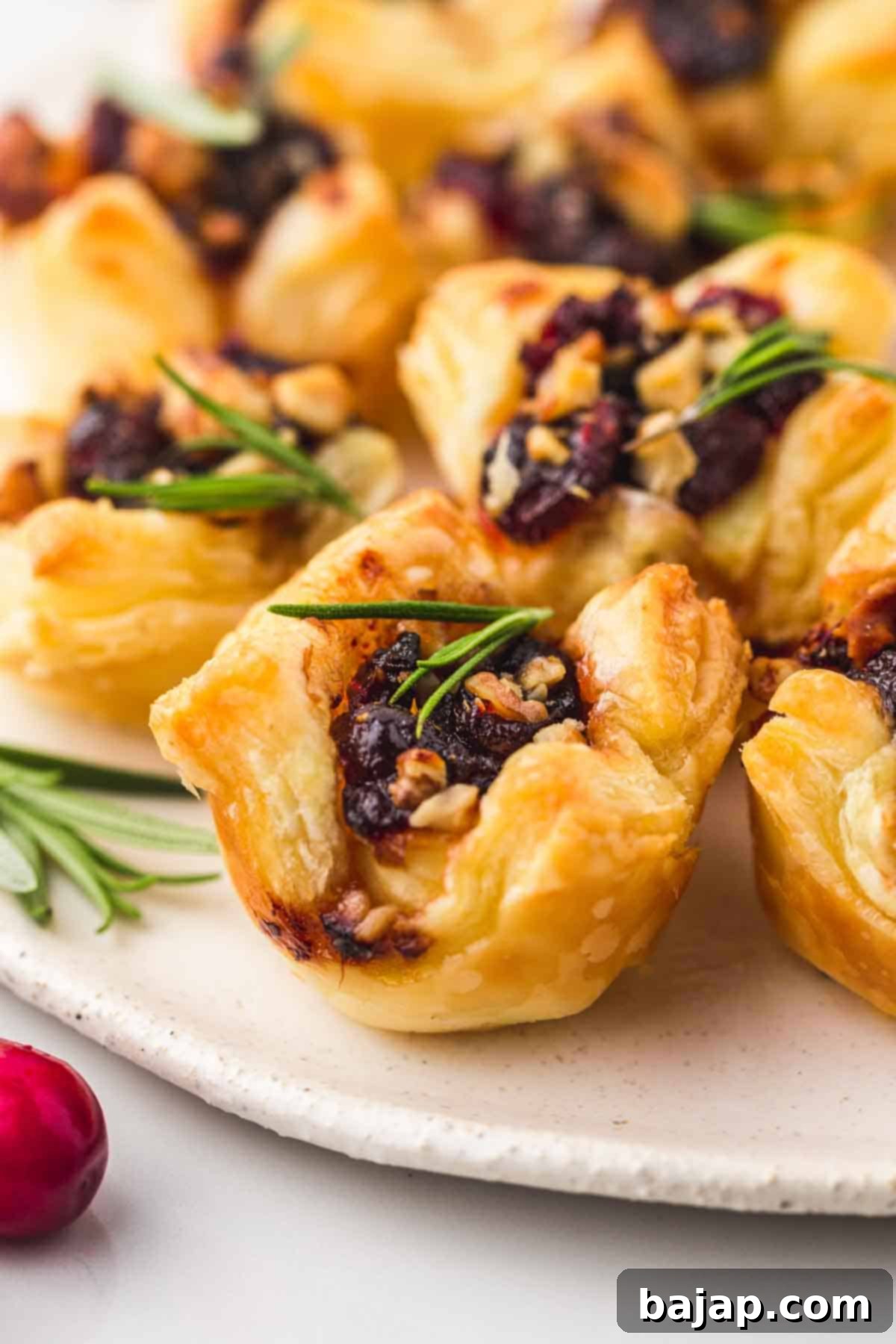 These easy cranberry brie bites make the perfect appetizer that tastes and looks fancy! Gooey melty cheese with tart cranberry sauce wrapped in a golden, buttery, and flaky puff pastry, to make these bite-sized snacks or appetizers for your next holiday gathering!