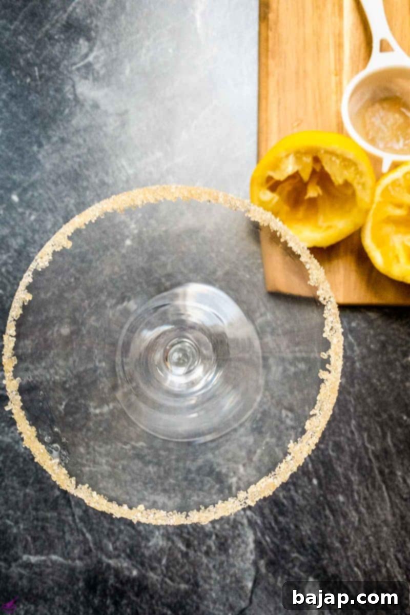 The perfect sugar rim being applied to a cocktail glass, a crucial step for the Snowball Cocktail presentation.