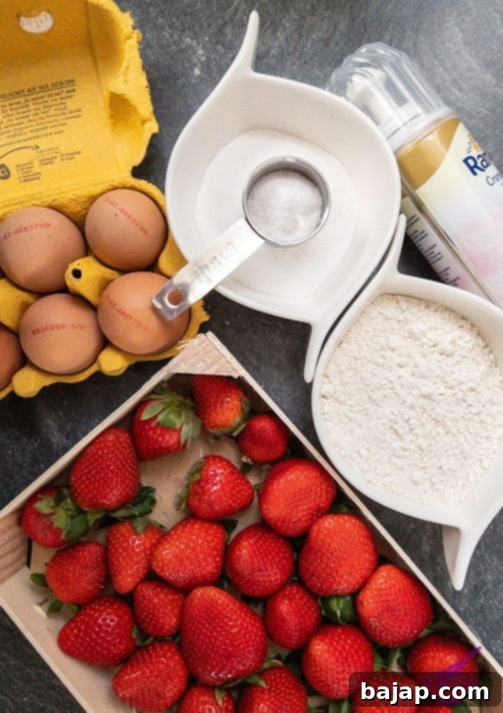 Strawberry Cloud Cake 3 Fresh ingredients laid out for baking a strawberry sponge cake including eggs, sugar, flour, and strawberries.
