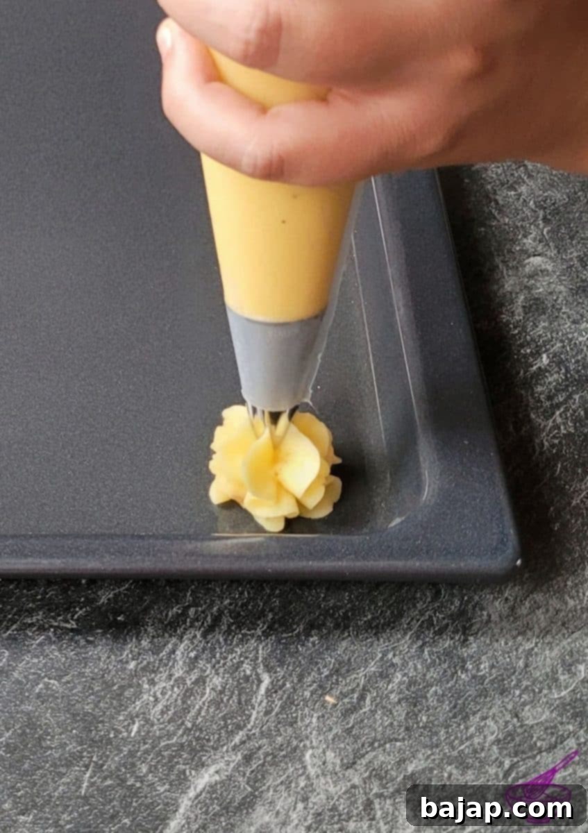 Piped duchess potato rosettes on a baking sheet