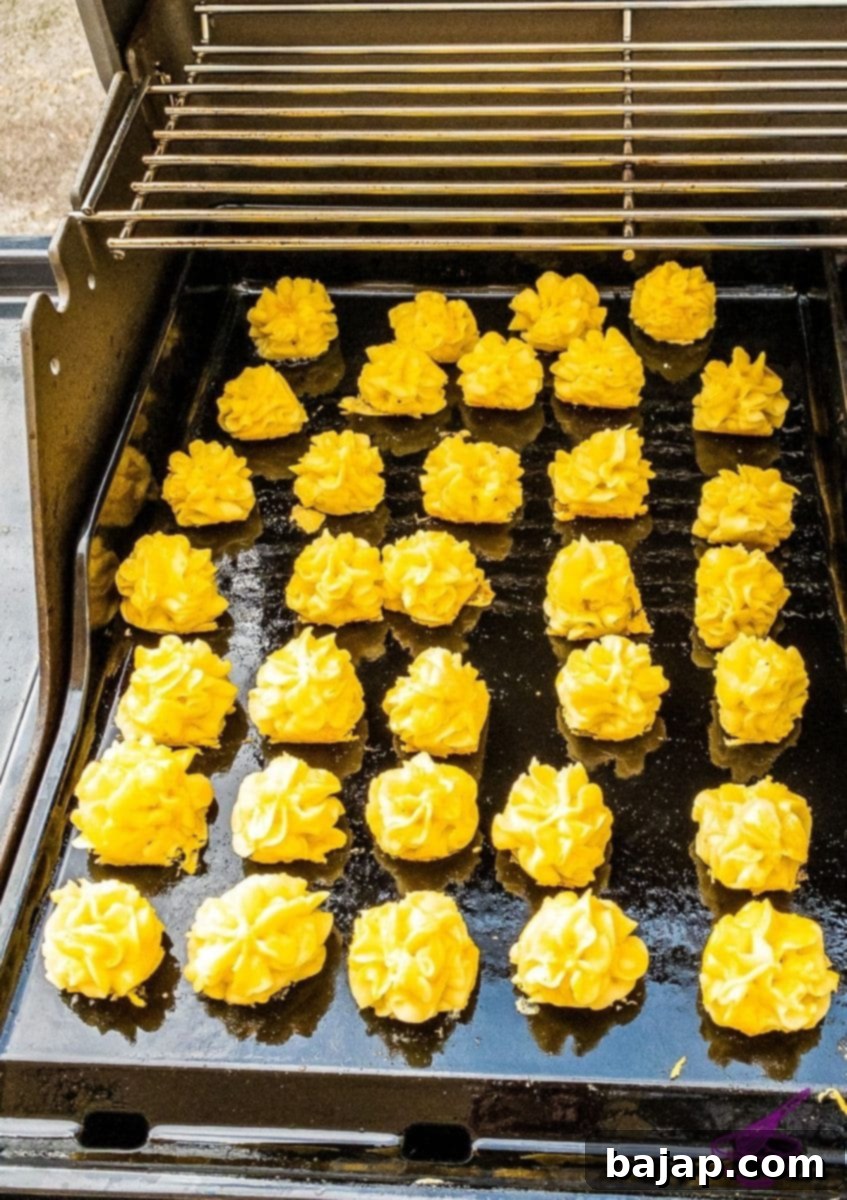 Oiling the hot plancha on the grill before adding piped mashed potatoes.