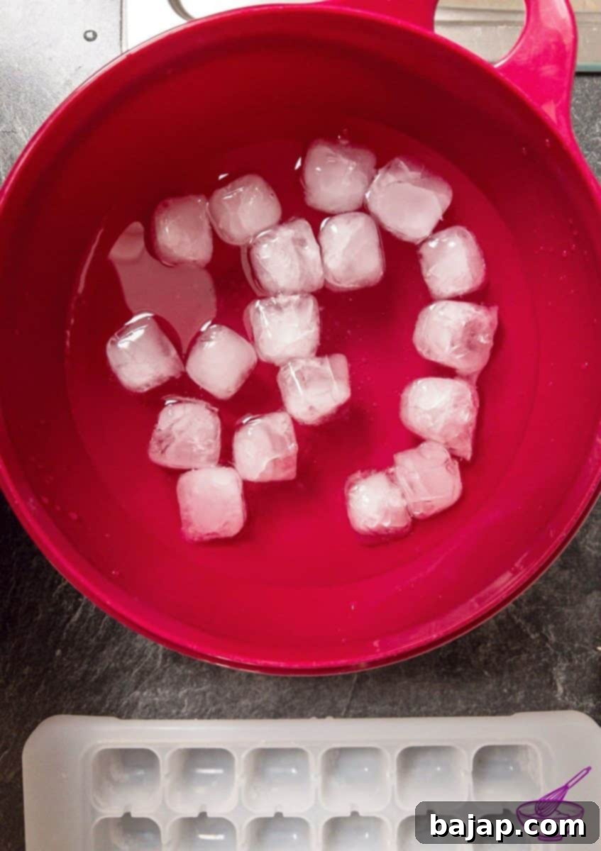 A large bowl filled with ice water and ice cubes, ready for shocking blanched vegetables.