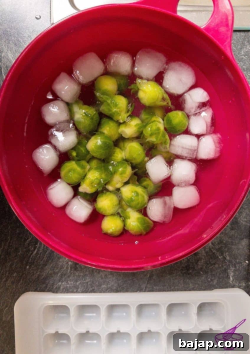 Blanched Brussels sprouts being transferred into an ice bath to stop the cooking process and preserve their vibrant color.