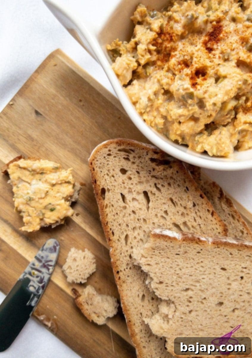 A vibrant bowl of Liptauer cheese spread, ready to be served, next to slices of fresh bread.