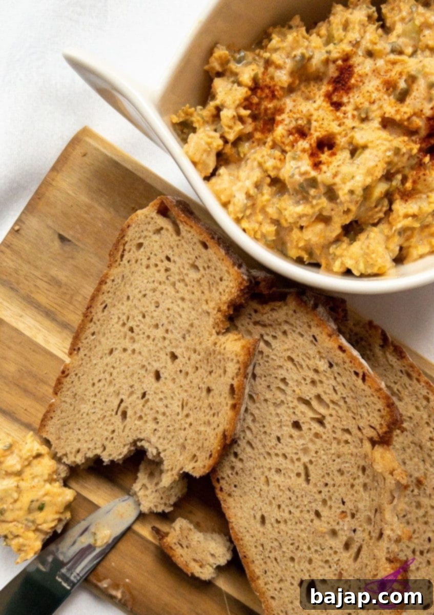 A serving of Liptauer cheese spread on a wooden board, garnished with fresh herbs, ready for a gathering.