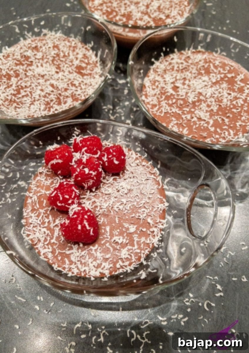 Dark chocolate mousse topped generously with fresh, vibrant raspberries, served in a clear glass.