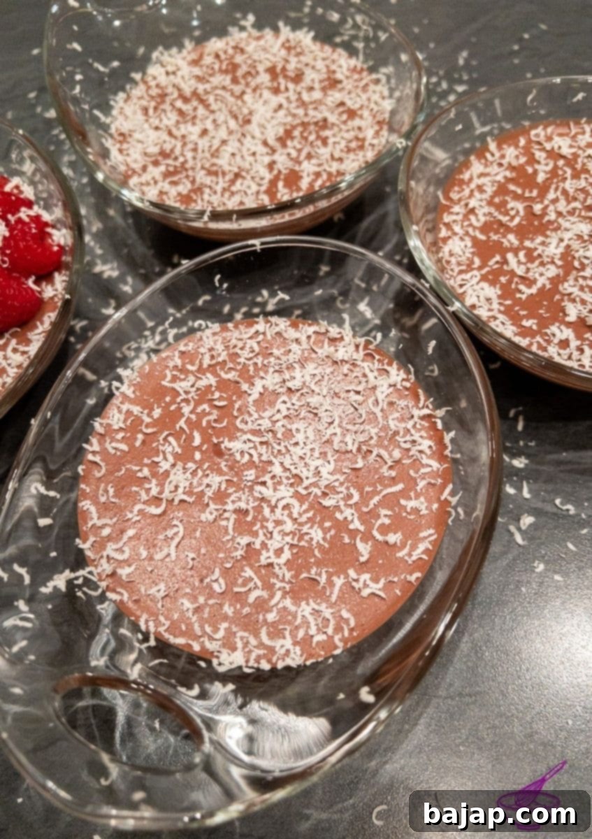 Dark chocolate mousse elegantly decorated with delicate white chocolate shavings, presented in a clear glass.