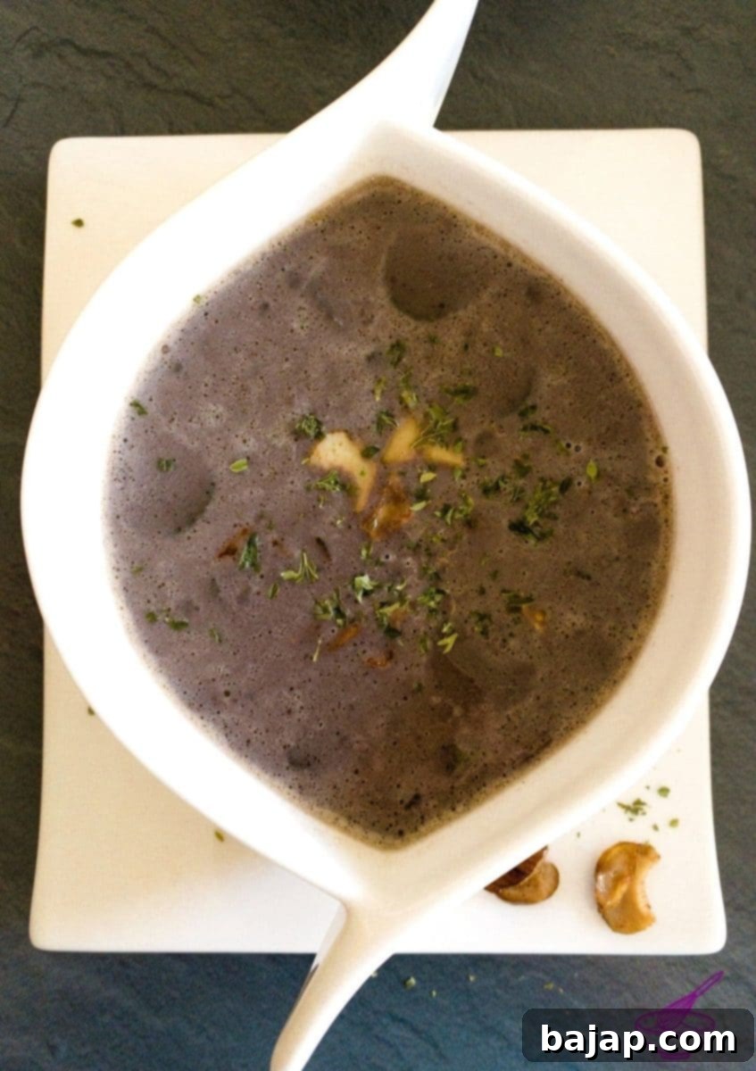 A bowl of creamy chestnut and porcini mushroom soup, garnished with fresh parsley and roasted porcini mushrooms.