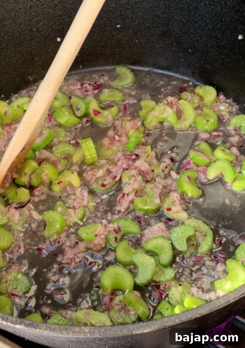 Onions and celery sautéing in a Dutch oven on a grill, ready for deglazing.