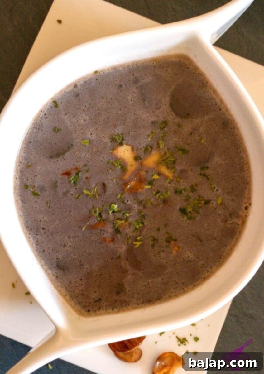 A beautifully presented bowl of chestnut and porcini mushroom soup, garnished with parsley, on a rustic table setting.