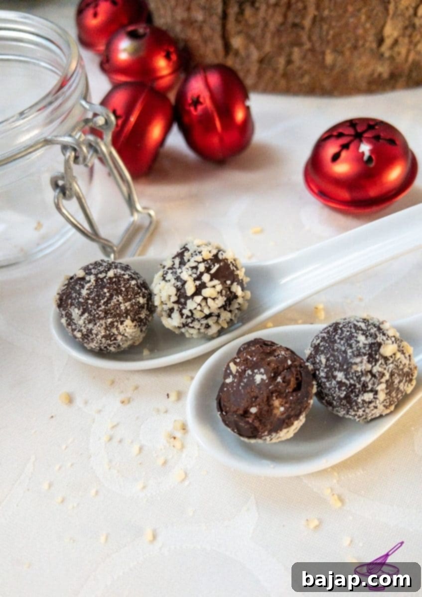Orange Marmalade Truffles with Dark Chocolate rolled in minced almonds on white tablecloth. Christmas decoration in the back.