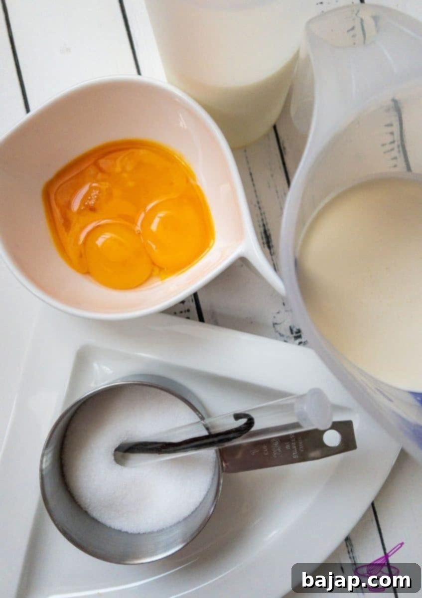 Fresh vanilla bean, high-fat milk, egg yolks, granulated sugar, and heavy cream laid out as ingredients for homemade ice cream.
