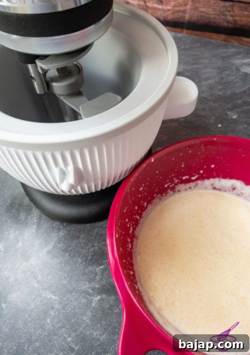 Thickened vanilla custard base cooling in a bowl, covered to prevent skin formation.
