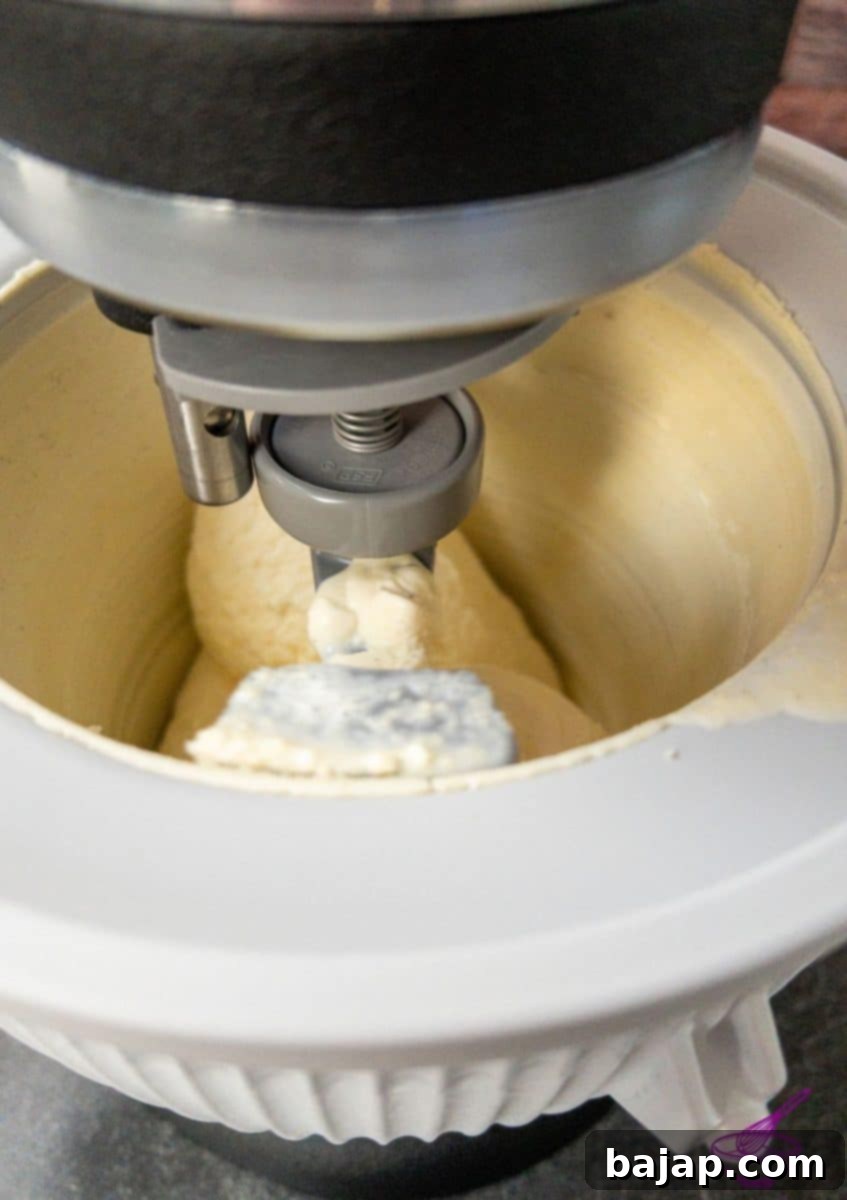 Homemade vanilla ice cream churning in a KitchenAid ice cream maker attachment.