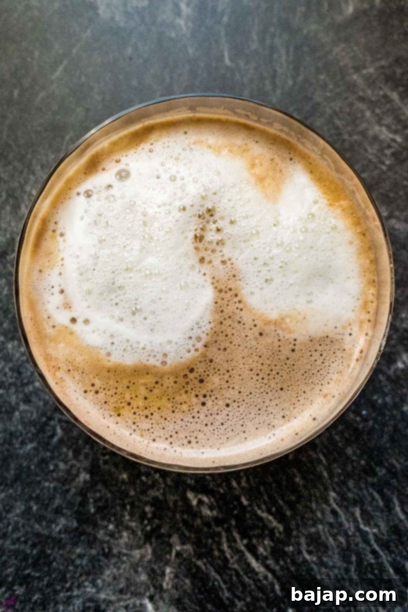 Close-up of freshly made eggnog hot chocolate with a generous layer of milk foam on top.