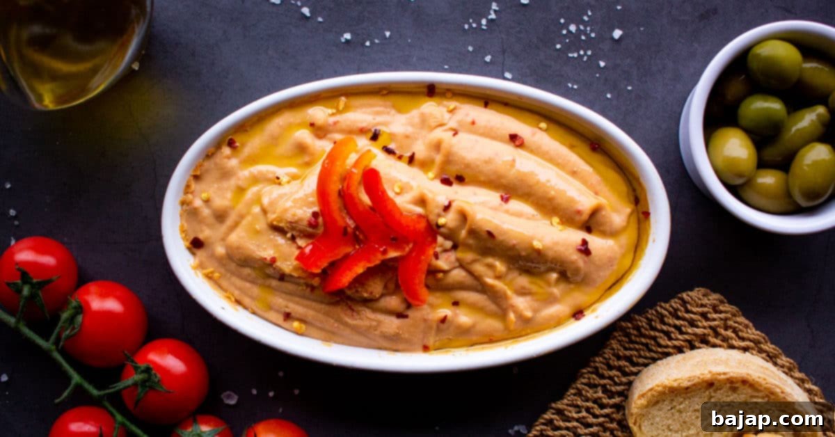 Red Pepper Hummus served in a bowl with pita bread.