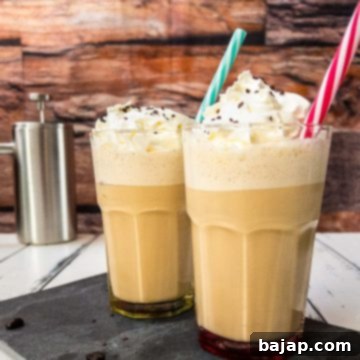 Two glasses filled with creamy Viennese iced coffee, garnished with whipped cream and chocolate sprinkles, with colorful straws.