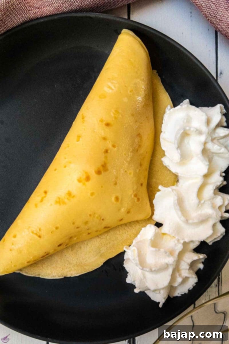 A scoop of vanilla ice cream placed on one half of a pancake, ready to be folded.